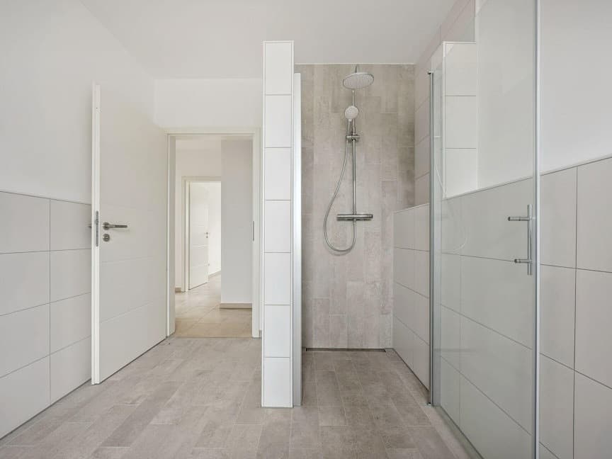 Badezimmer mit Walk-in-Dusche, weissen Wandfliesen und grauem Bodenbelag