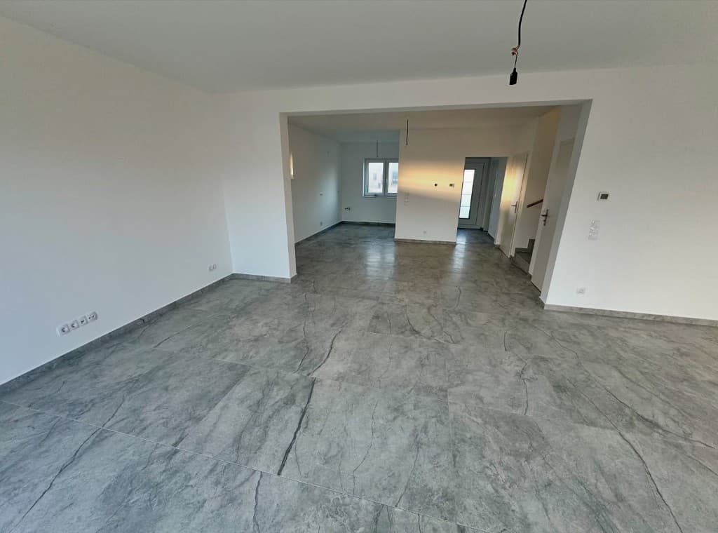 Leerer grosser Raum mit grau marmorierter Bodenfliese und weissen Wänden