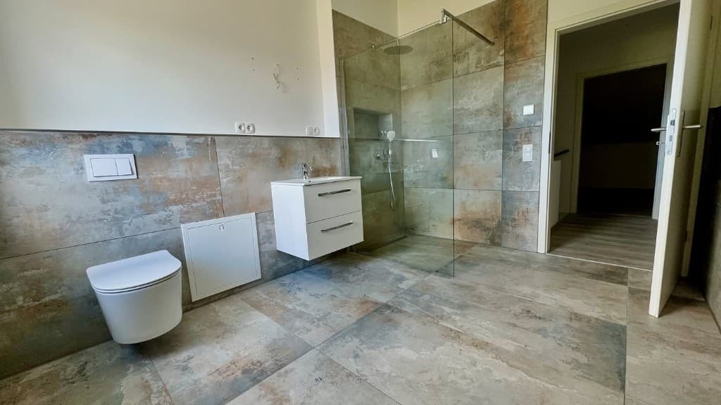 Modernes Bad mit Steinoptik-Fliesen, Wand-WC, Waschtisch und Walk-in-Dusche